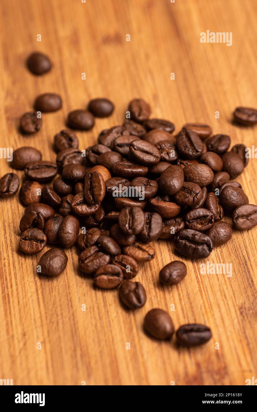 Chicchi di caffè arrostiti marroni pelo piccolo su un macrofone di legno. Foto Stock