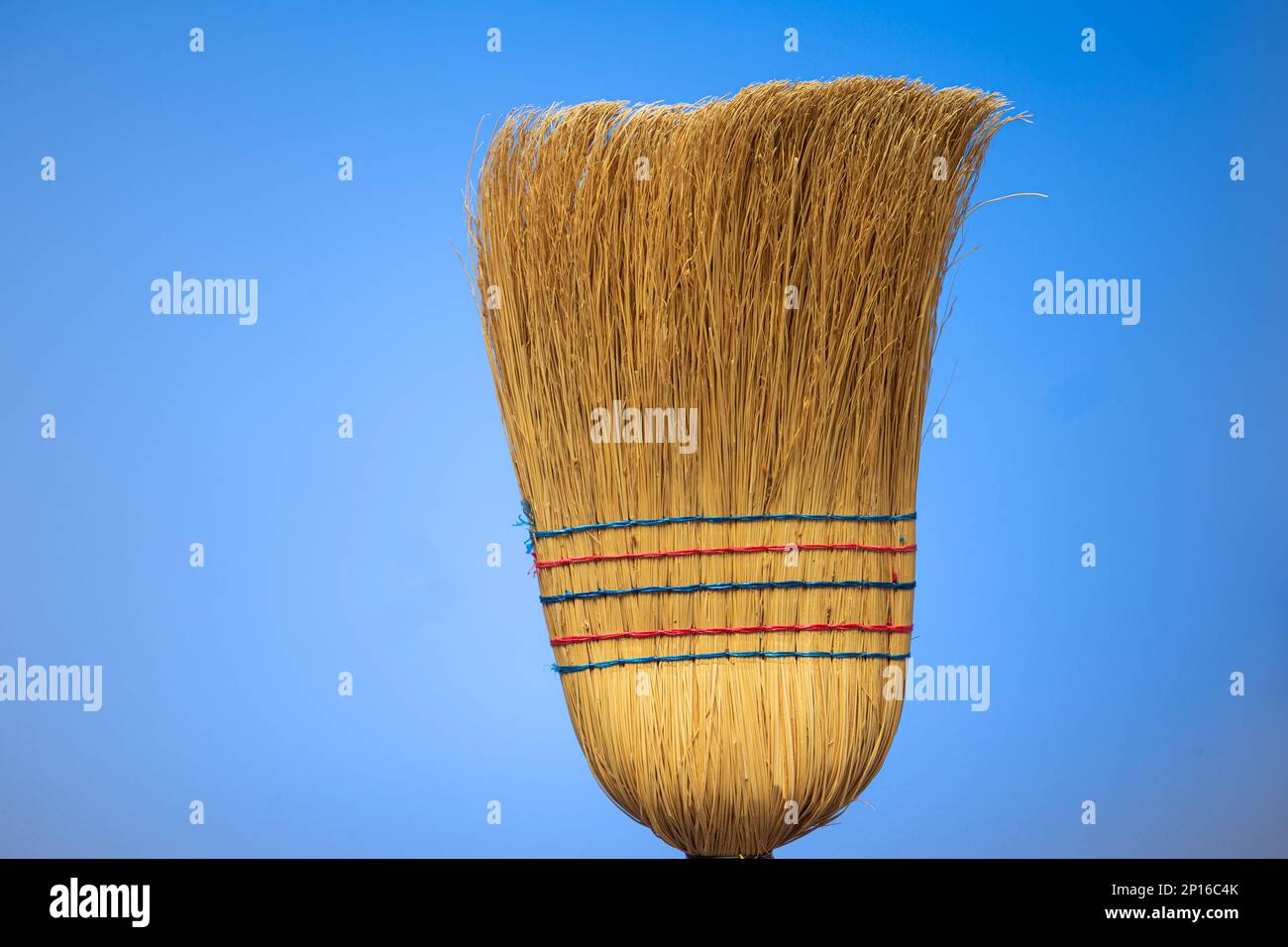 Dettaglio primo piano della scopa intrecciata isolato su sfondo blu. Foto Stock