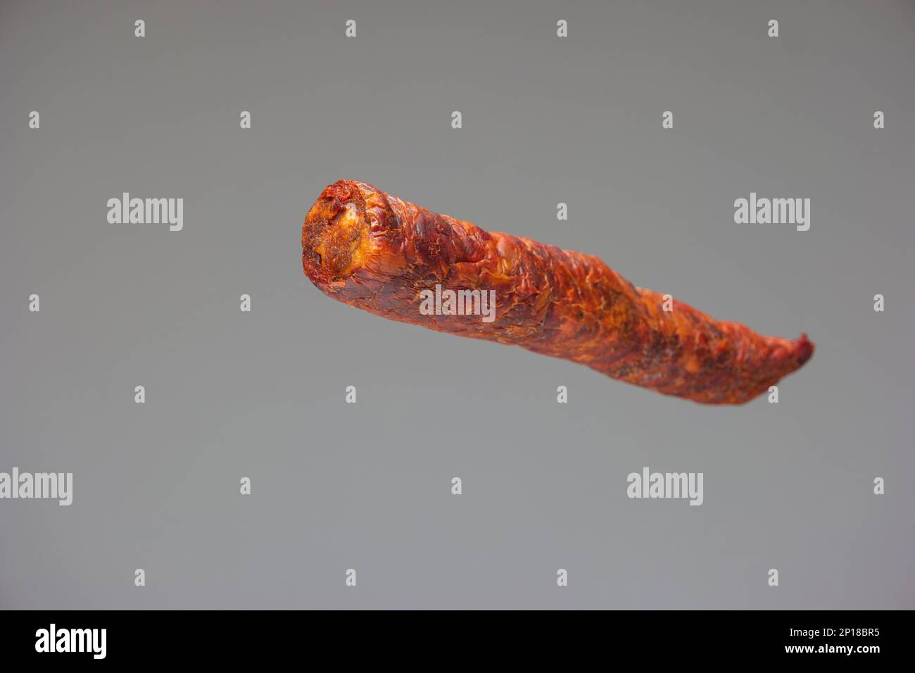 Salsiccia speziata affumicata in stile ungherese primo piano scatto studio isolato su sfondo grigio. Foto Stock