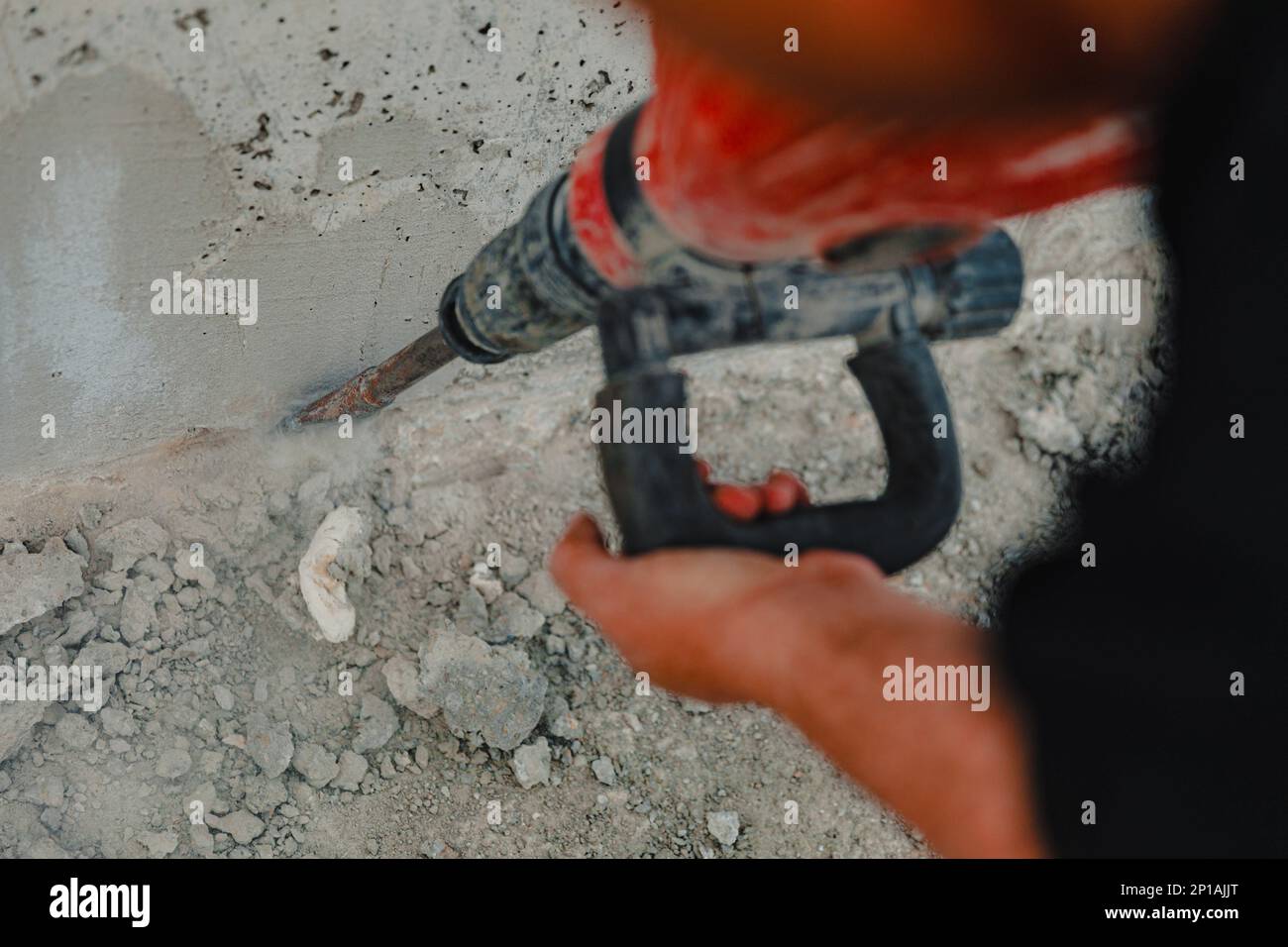 Vista di un lavoratore in un cantiere che lavora con una perforatrice da roccia e che scava il terreno Foto Stock
