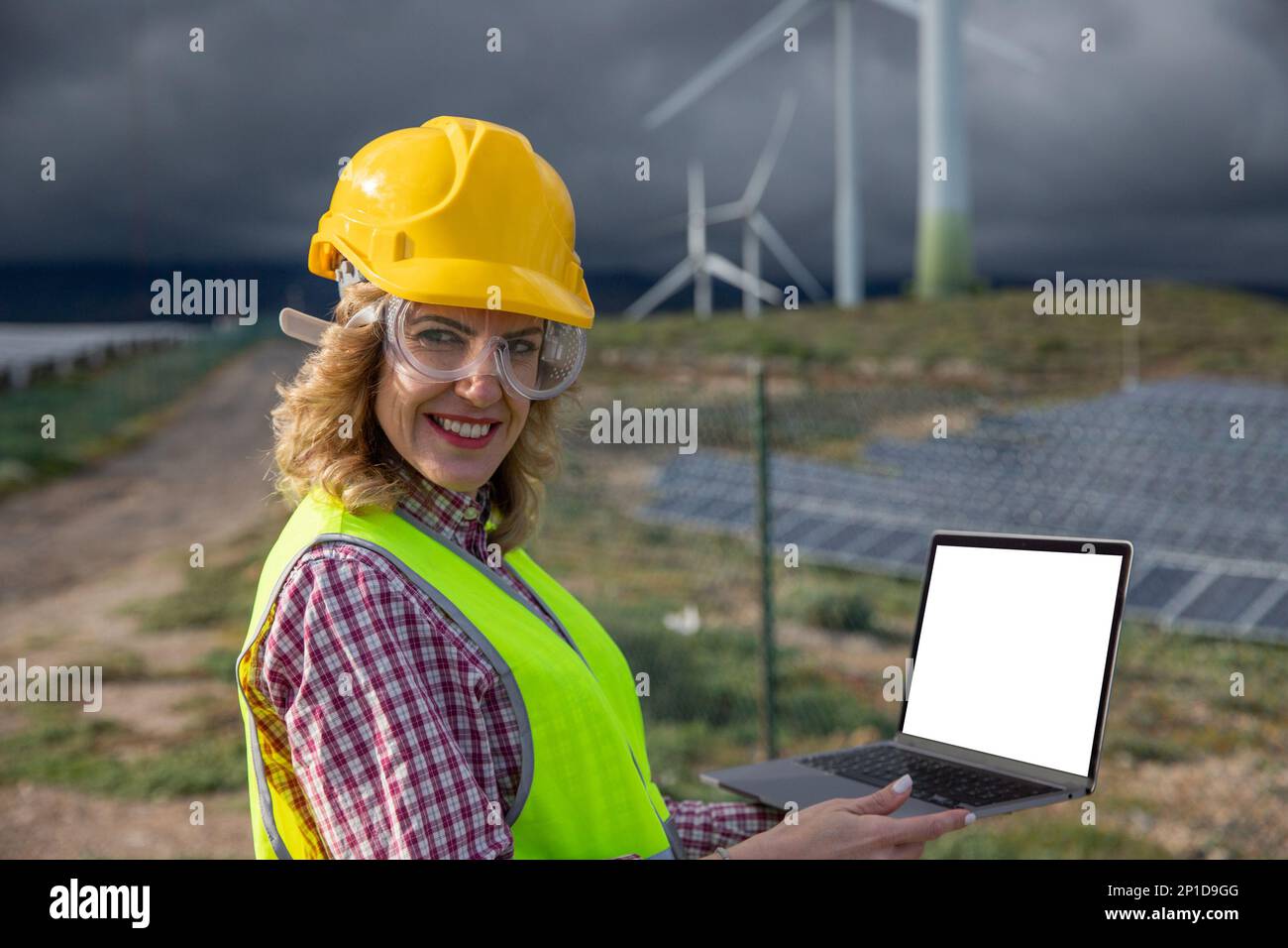 L'ingegnere femminile usa il suo computer portatile mentre lavora in una centrale solare, schermo con mockup. Foto Stock