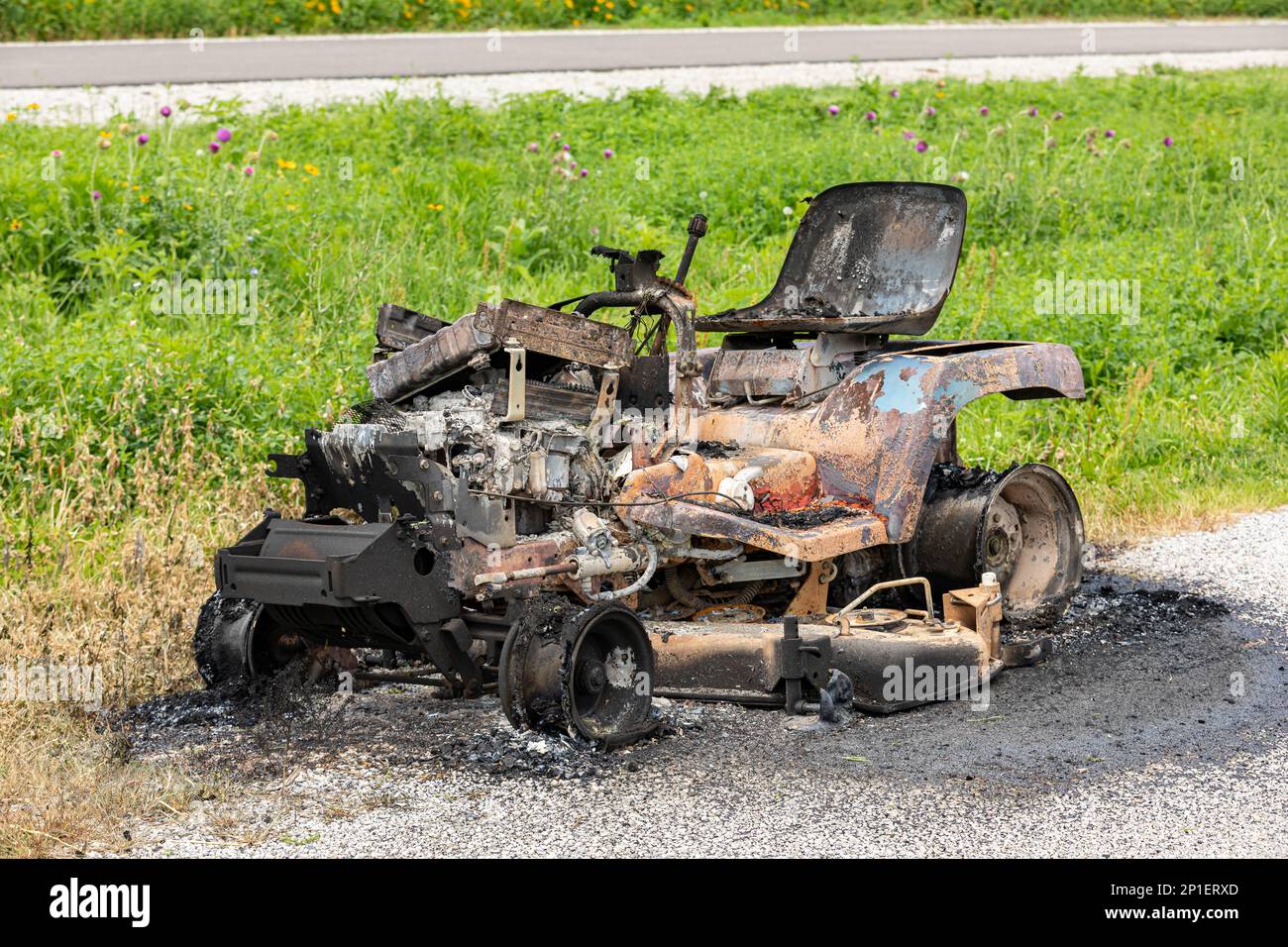 Trattore rasaerba danneggiato dal fuoco. Manutenzione attrezzature per prato, riparazione e concetto di assicurazione proprietari di casa. Foto Stock