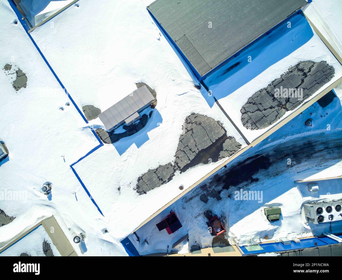 Vista sopraelevata del drone di un edificio con tetto piatto con unità di ventilazione e carico di neve. Foto Stock