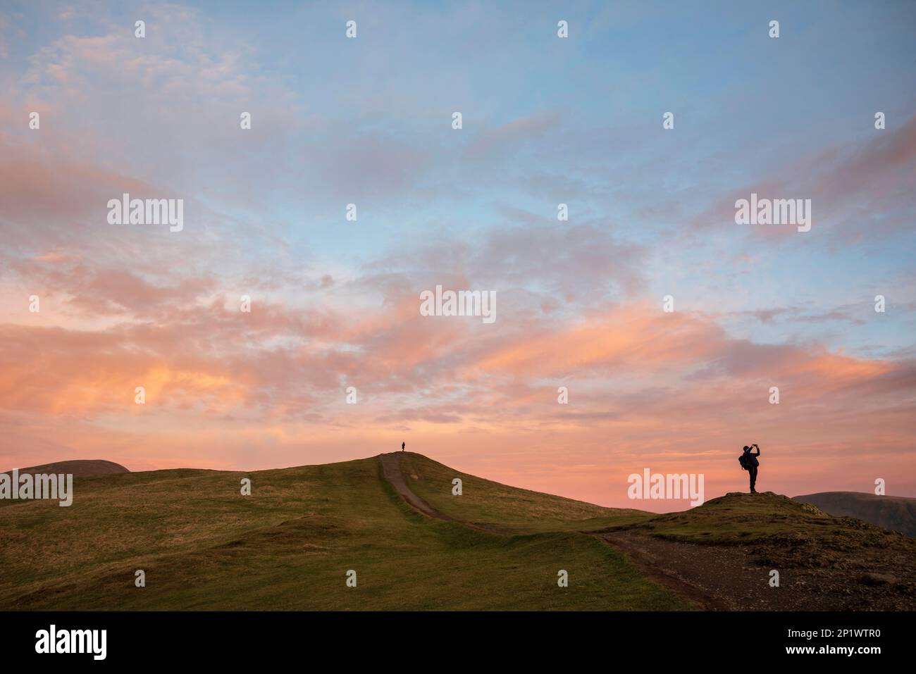 Il bellissimo paesaggio del tramonto invernale sopra Latrigg è caduto nel Lake District con due persone in cima alla collina che ammirano il tramonto Foto Stock