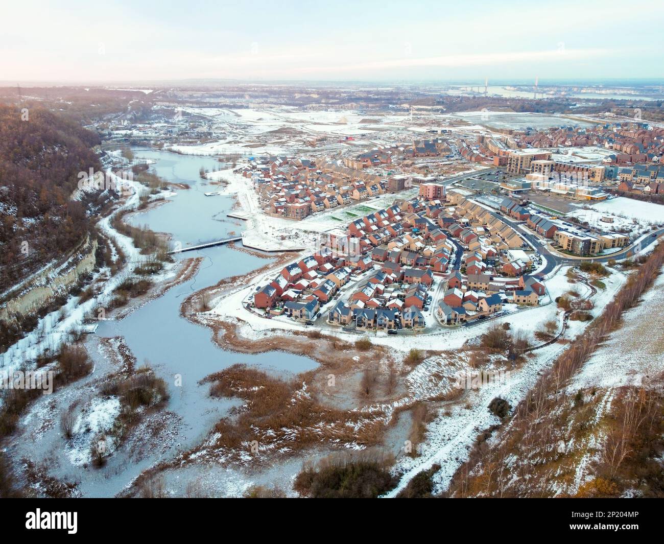 Drone aereo. Ebbsfleet città giardino nel Kent, coperto di neve nel dicembre 2022. Nuovi sviluppi e lago ghiacciato lungo l'autostrada A2. Foto Stock