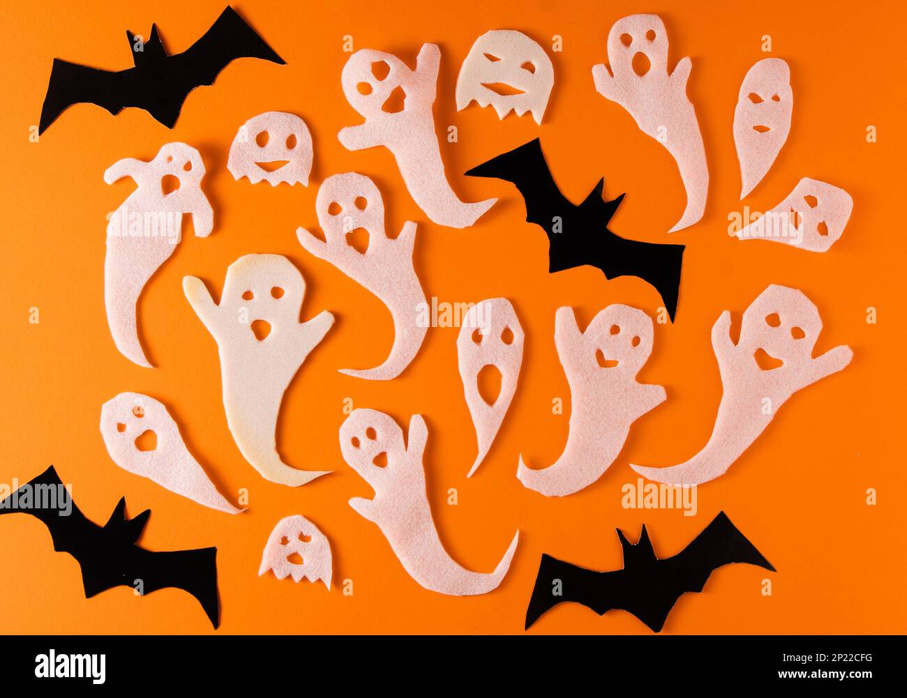 Fantasmi bianchi e mazza per la festa di Halloween. Immagine fantasma della carta di avvolgimento su sfondo arancione vista dall'alto. Fumetto Creepy Whisper. Fai-da-te fatto a mano. Impostare i caratteri boo. Foto Stock