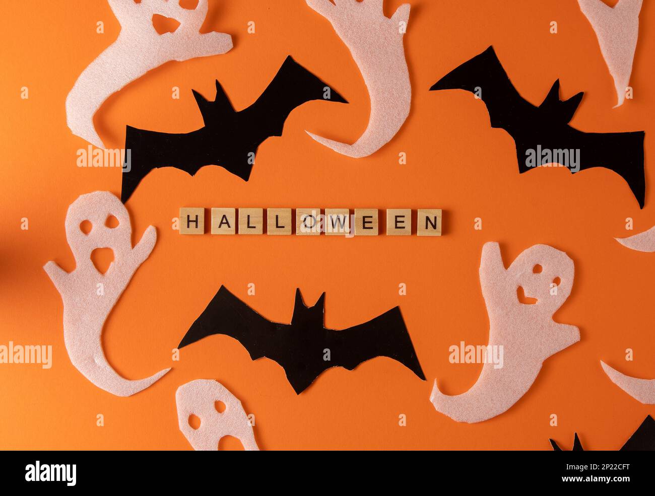 Fantasmi bianchi e mazza per la festa di Halloween. Immagine fantasma della carta di avvolgimento su sfondo arancione vista dall'alto. Fumetto Creepy Whisper. Fai-da-te fatto a mano. Impostare i caratteri boo. Parola frase di legno della lettera. Foto Stock