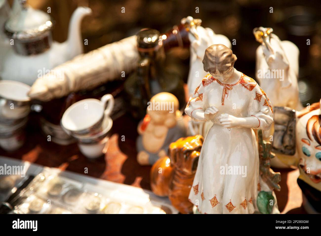 Porcellana antica donna e altre figurine e stoviglie presso il mercato delle pulci . Vecchia ragazza di ceramica statuetta e Cina vasellame collectibles presso il garage Foto Stock