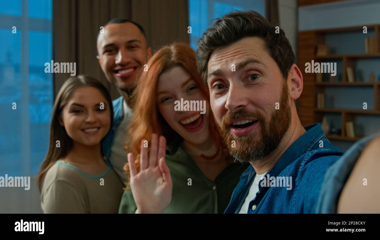 Barbuto uomo blogger tenere in mano telefono cellulare invitare amici colleghi per foto di gruppo uomini diversi donne etnico multirazziale persone che guardano in macchina fotografica Foto Stock