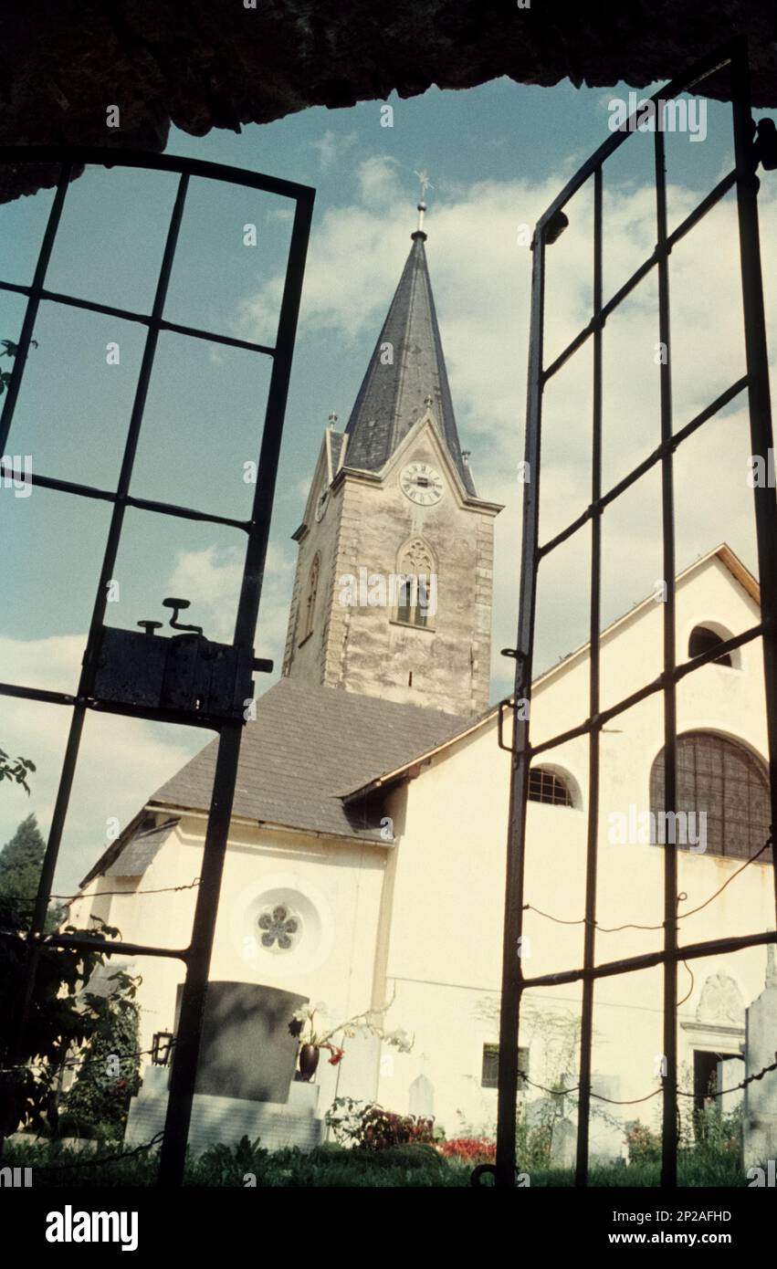 Vista attraverso una porta di ferro al cimitero e la chiesa parrocchiale Mariae Himmelfahrt dell'ex Abbazia di Ossiach, Ossiach, Carinzia, Austria, 1968 Foto Stock