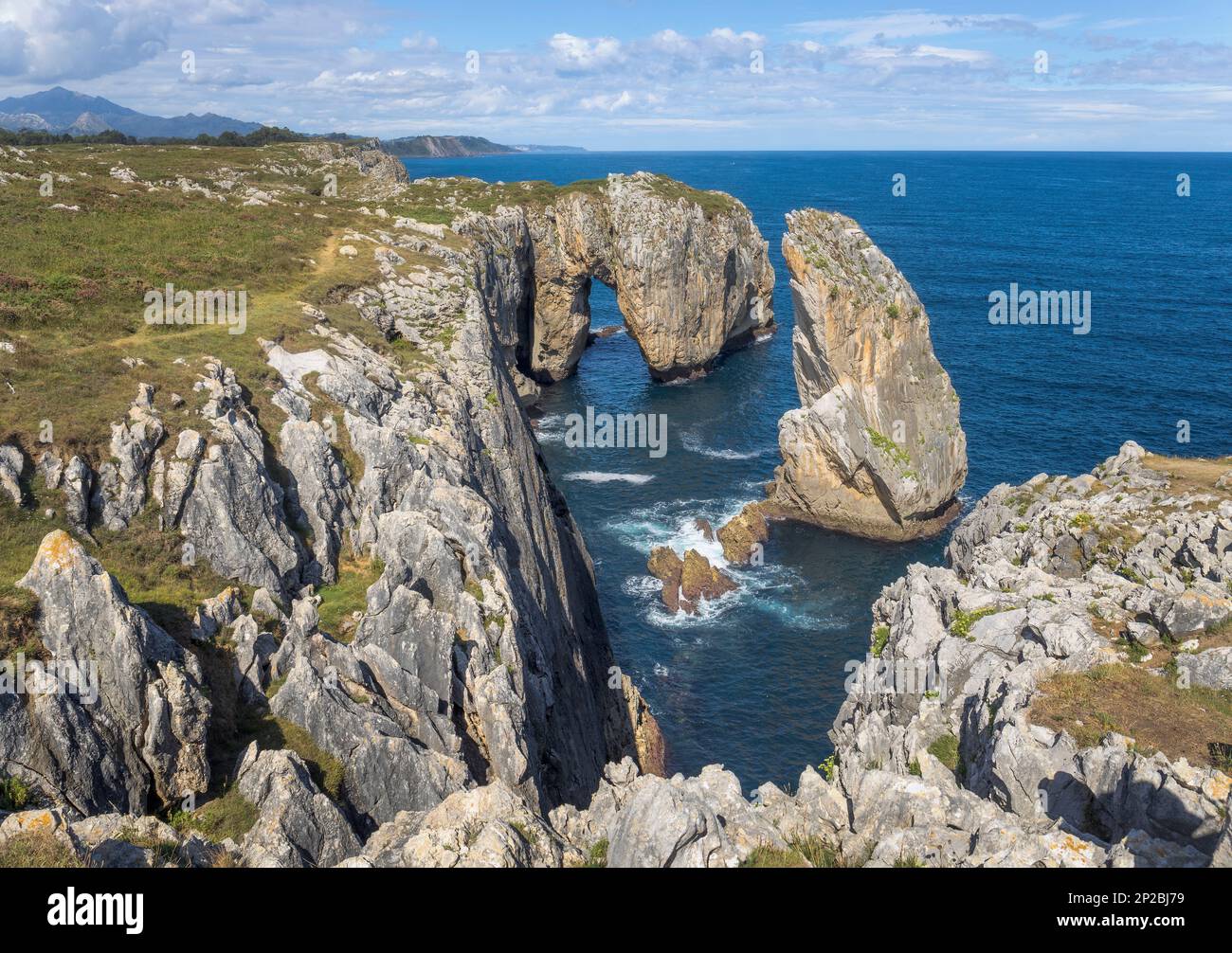 Una tranquilla scena delle scogliere dell'Inferno nelle Asturie, la Spagna rivela una spettacolare costa rocciosa che si estende dal mare ad una formazione rocciosa impressionante circondata b Foto Stock