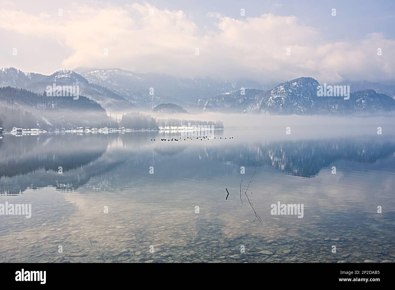 Paesaggio innevato con neve, con specchio sull'acqua del lago sotto il cielo nuvoloso Foto Stock