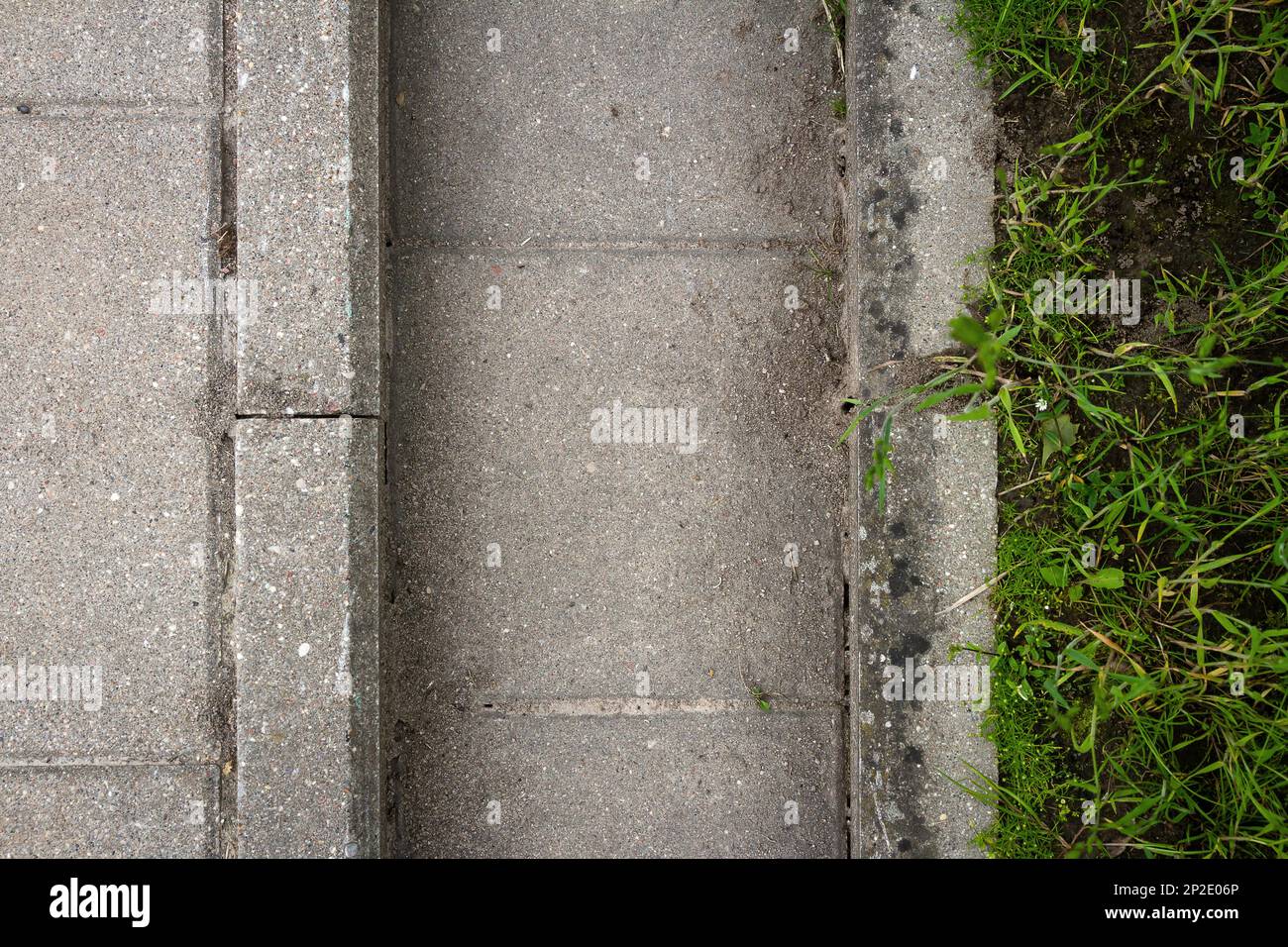 Il sistema di drenaggio dell'acqua di fusione, dei flussi di pioggia e delle inondazioni. Primo piano di piastrelle di cemento ed erba. Foto Stock