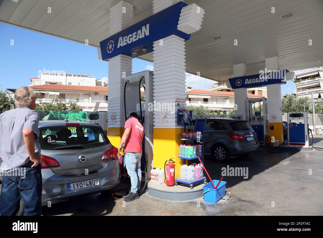 L'uomo della stazione di benzina dell'Egeo che riempie l'automobile alle pompe sulla strada all'aeroporto internazionale di Atene Grecia Foto Stock