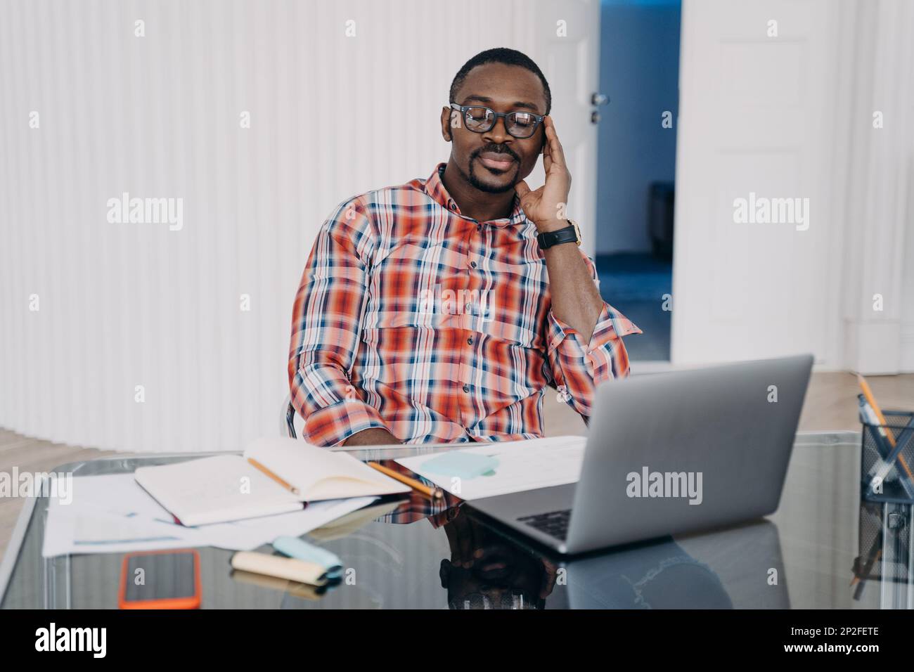 Lavoratore afroamericano stanco maschio con gli occhi chiusi tenere la testa con la mano rilassarsi, fare una pausa sul posto di lavoro. L'uomo nero penoso al laptop raccoglie i pensieri Foto Stock