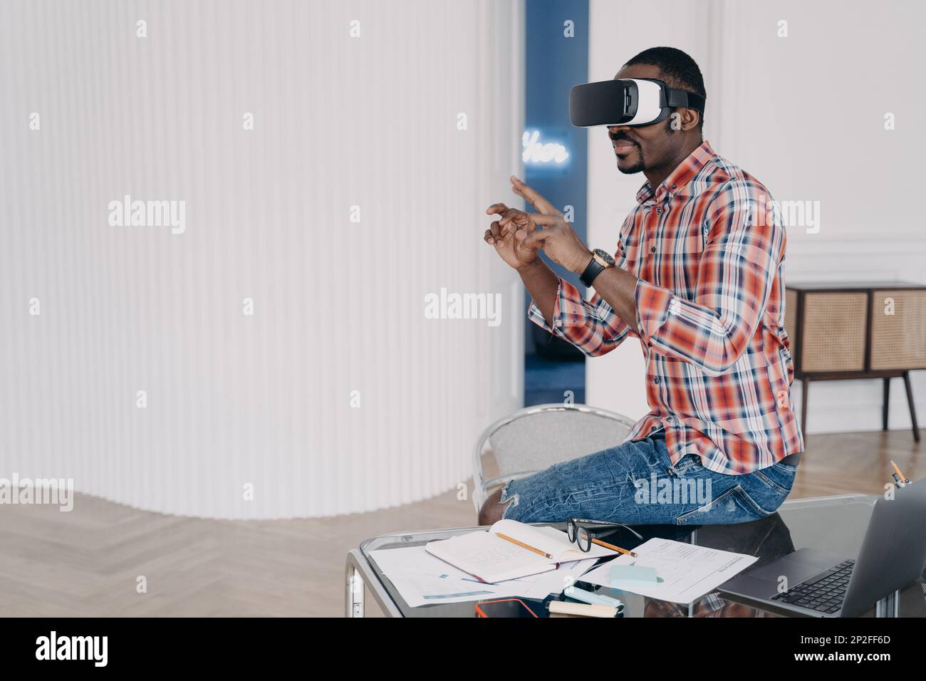 Uomo d'affari ha corso virtuale. Uomo afroamericano in occhiali vr a casa. Auricolare per realtà virtuale che utilizza un dispositivo elettronico. Istruzione moderna e scavo Foto Stock