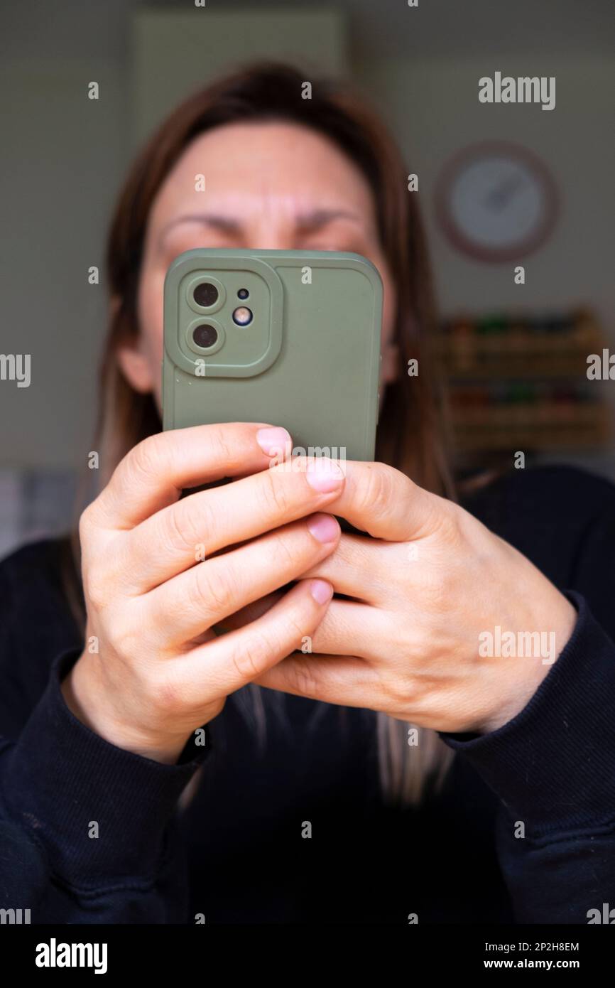 Giovane donna mani tenere il telefono cellulare iphone SMS messaggi guardando lo schermo offuscato viso UK 2023 KATHY DEWITT Foto Stock