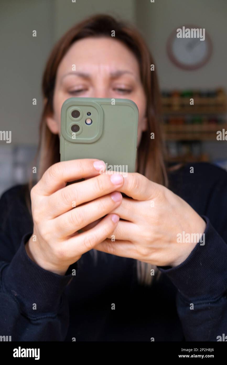 Giovane donna mani tenere il telefono cellulare iphone guardando lo schermo offuscato viso UK 2023 KATHY DEWITT Foto Stock
