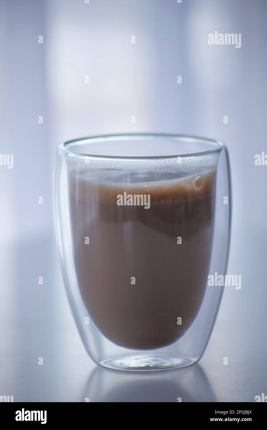 Caffè con latte in un bicchiere trasparente a doppio fondo. Una bevanda popolare in un bicchiere originale Foto Stock