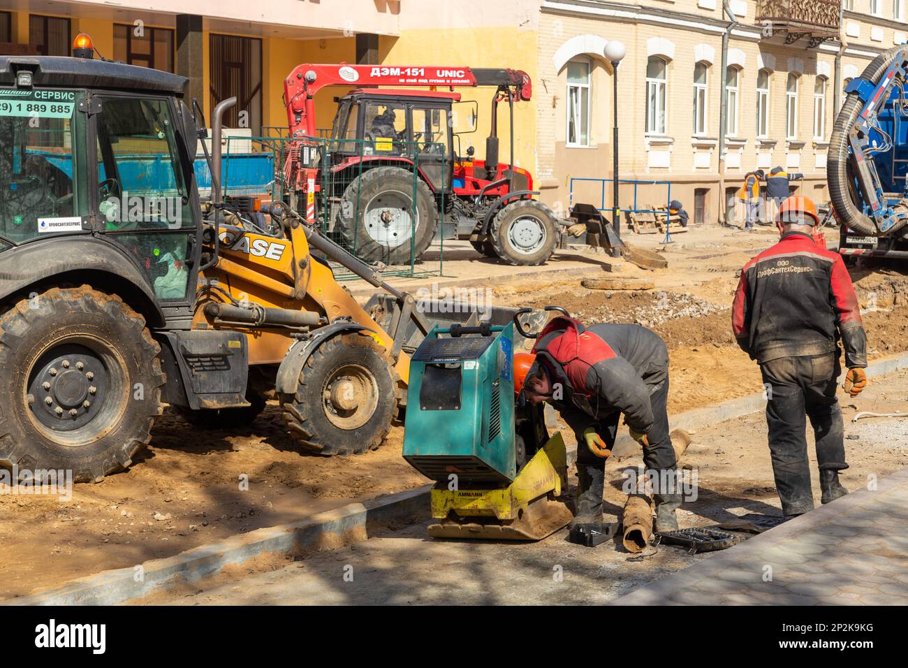 Grodno, Bielorussia - 06 marzo 2022: I lavoratori con l'aiuto di attrezzature per il movimento terra stanno ricostruendo le utenze sotterranee su una delle strade più antiche Foto Stock