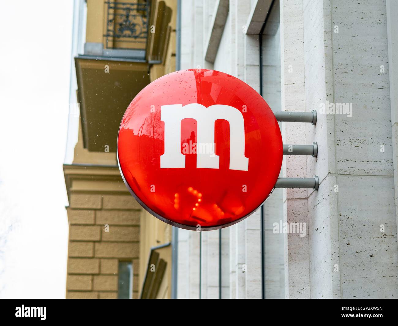 Cartello rosso M dragee sulla facciata di un edificio. Pubblicità per il negozio m&m a Berlino. Marca di cioccolato della società Mars. Dolci americani popolari. Foto Stock