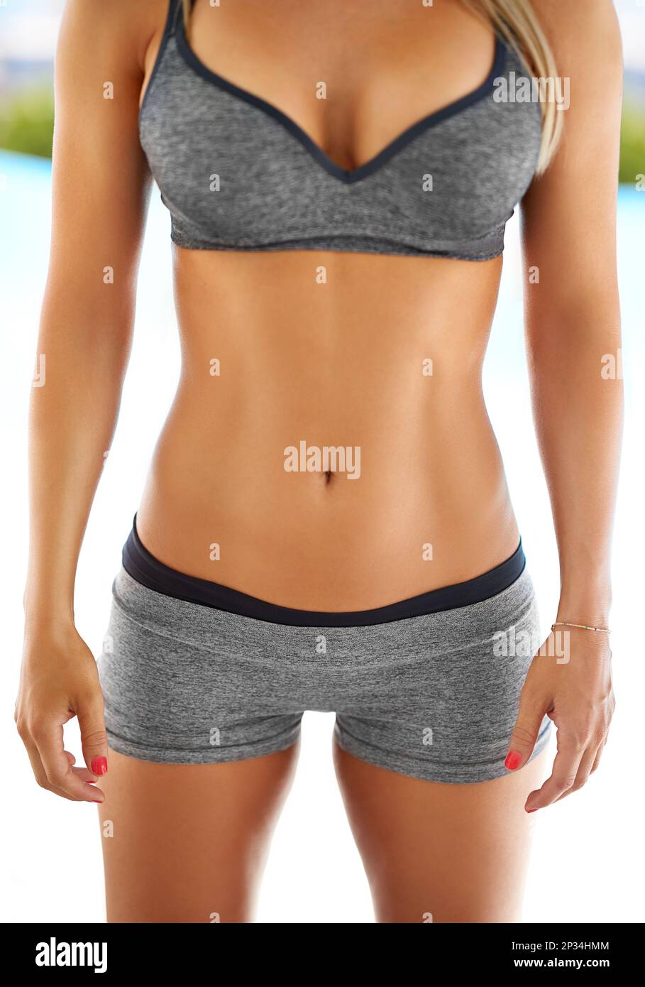 Prendi la pancia piatta ora. una donna con uno stomaco tonificante che si posa all'aperto in abbigliamento sportivo. Foto Stock