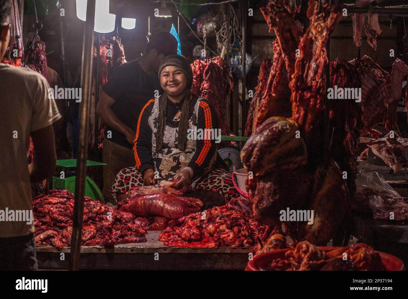 Una donna musulmana sorridente taglia la carne cruda per venderlo di notte nel principale mercato all'ingrosso della carne, Phsar Dumkor. Phnom Penh, Cambogia. © Kraig Lieb Foto Stock