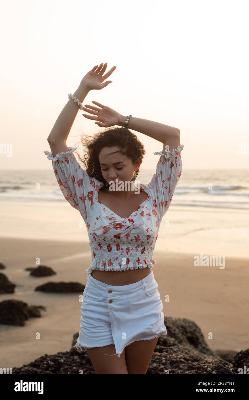 Bella giovane donna in riva al mare contro il tramonto, chiudendo gli occhi, completamente staccata da tutto. Foto Stock