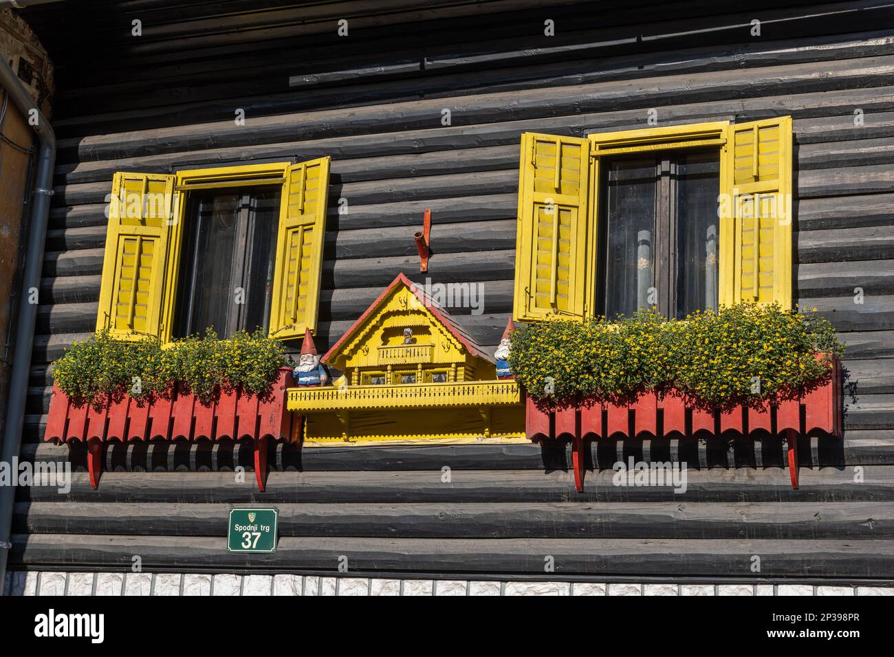Skofja Loka, Slovenia, casa unica su Spodnji trg 37 con tradizionale facciata in legno, decorata con statuette nane che custodiscono una piccola casa con una bambola Foto Stock
