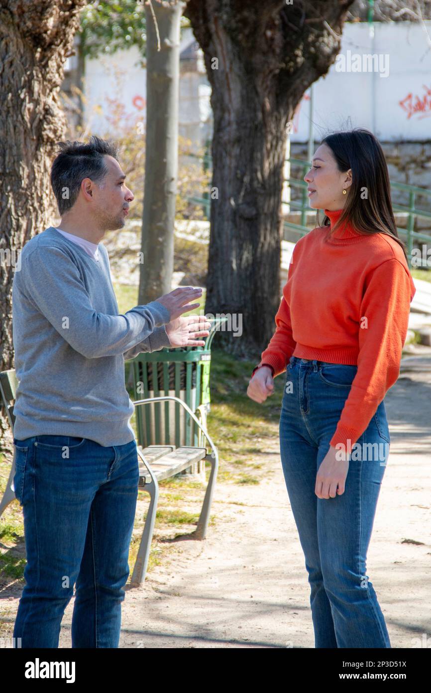 Coppia di un uomo maturo e di una giovane donna, chiacchierando e condividendo il loro tempo, in giardino in una giornata di sole Foto Stock