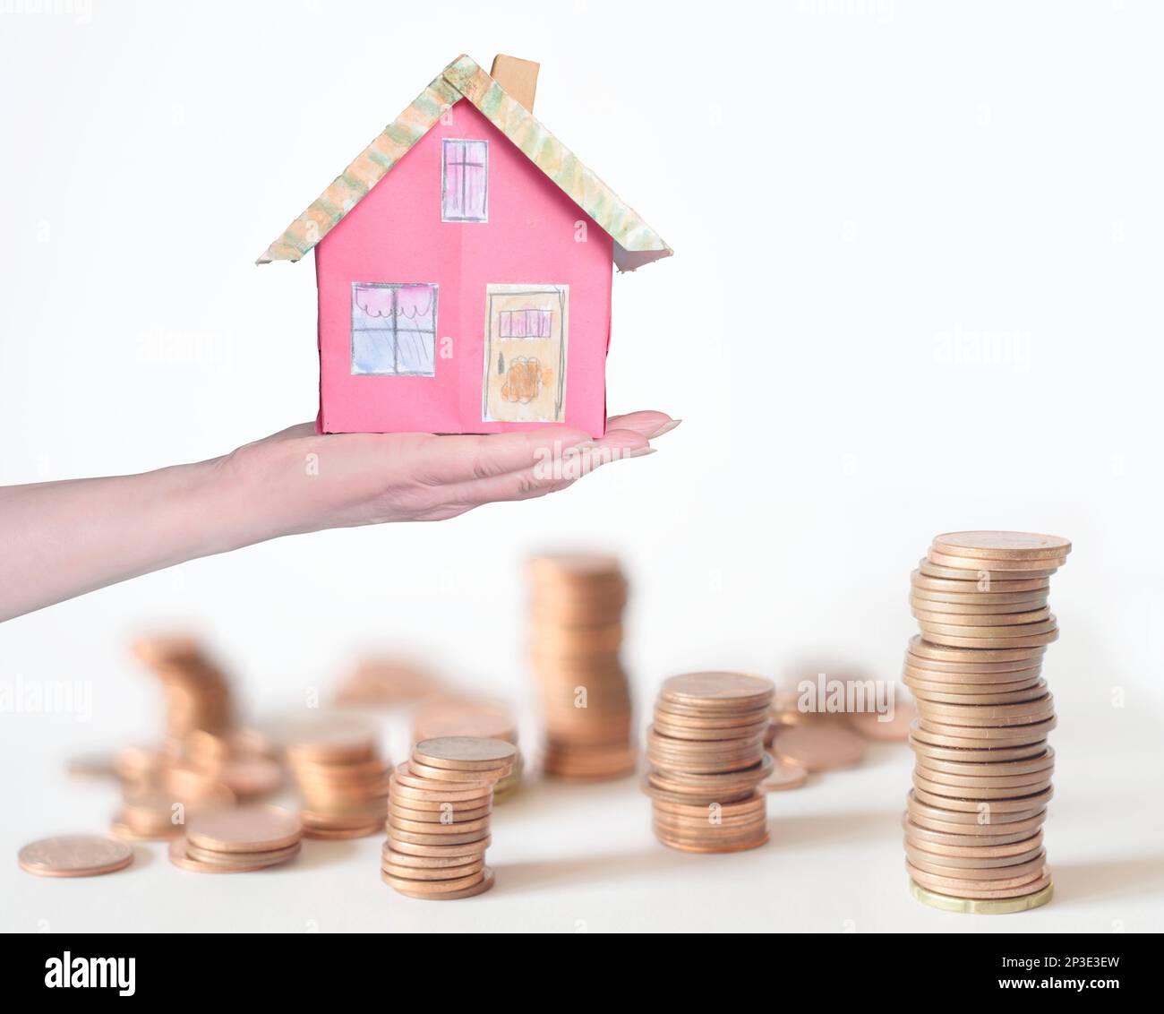 rendite crescenti, tassi di interesse, costi di riscaldamento, spese di vita, casa modello sulla mano femminile con i soldi impilati nello sfondo, concettuale, pictur simbolico Foto Stock
