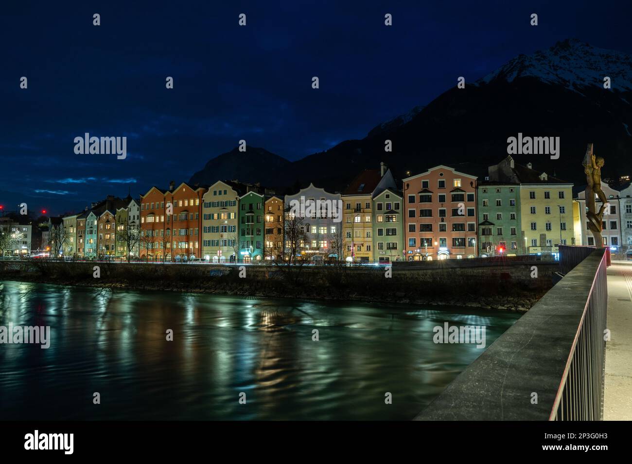 Belle case colorate fiancheggiano la riva del fiume della storica città di Innsbruck, si trova in una valle di montagne innevate Foto Stock