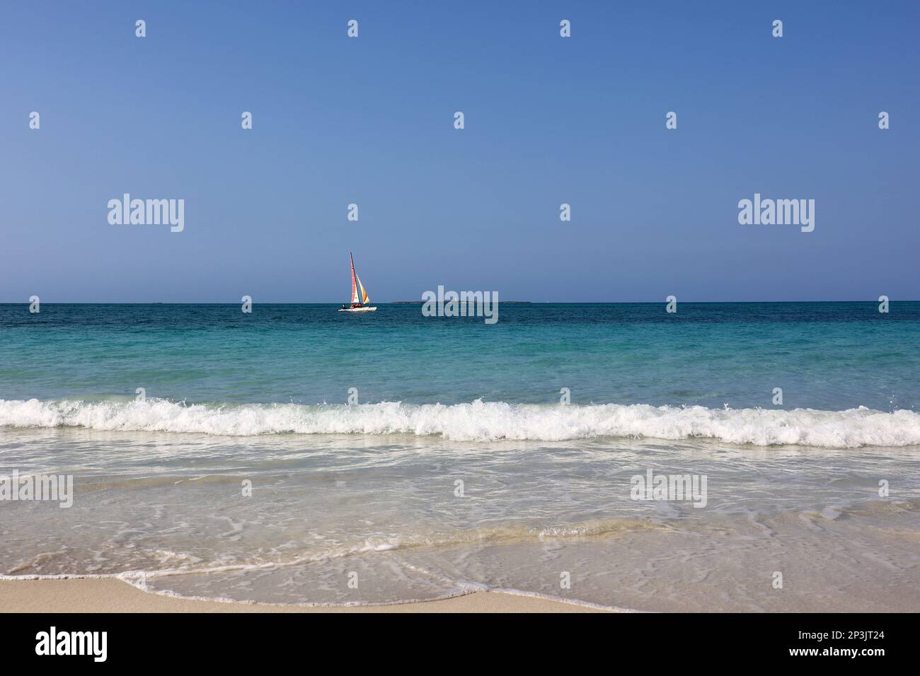 Onde blu che si infrangono su sabbia bianca, spiaggia tropicale con barca a vela in oceano. Sfondo per vacanze in una natura paradisiaca Foto Stock