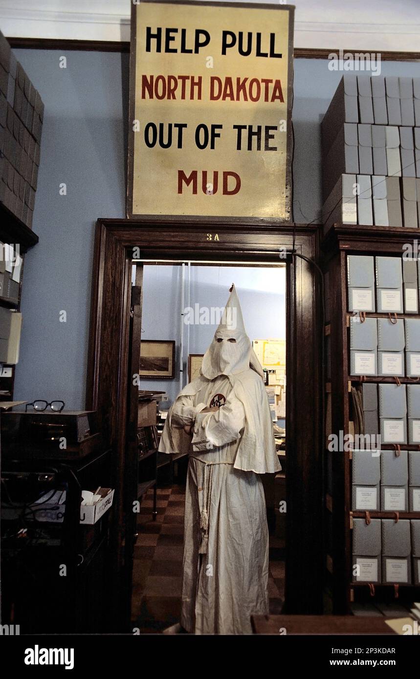 Due manufatti non correlati del museo del 1920s con un vestito con cappuccio KKK Ku Klux Klan del Nord Dakota e uno slogan del governo federale e un cartello della campagna f Foto Stock