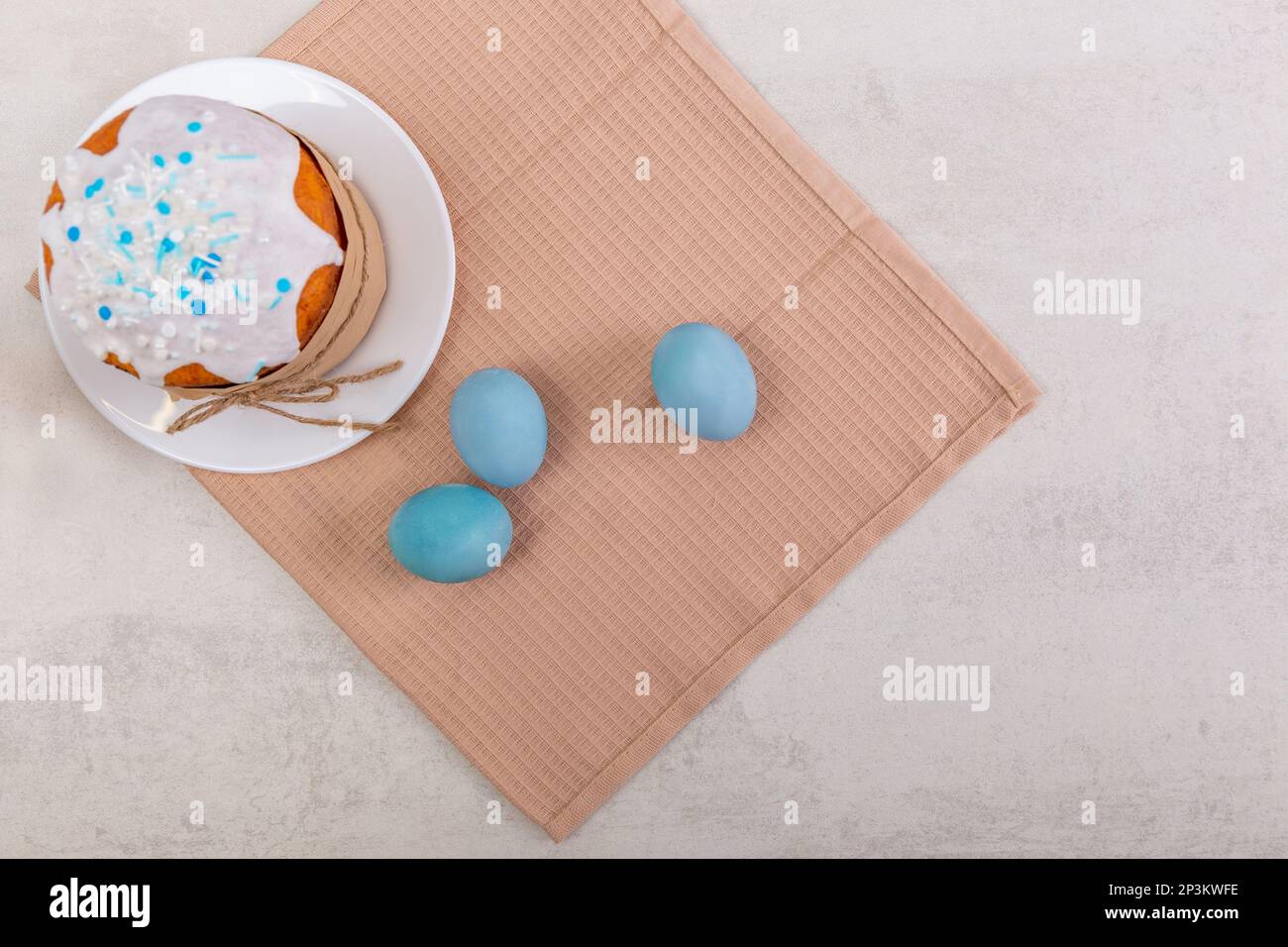 Pasqua torta russa e uova colorate su un tovagliolo, su un tavolo leggero. Buon poster di pasqua e banner per il testo di saluto. Vista dall'alto Foto Stock