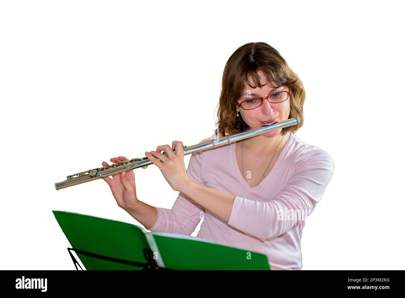 Una giovane flutista femminile suona un flauto di strumenti a vento e guarda le note, isolate su uno sfondo bianco Foto Stock