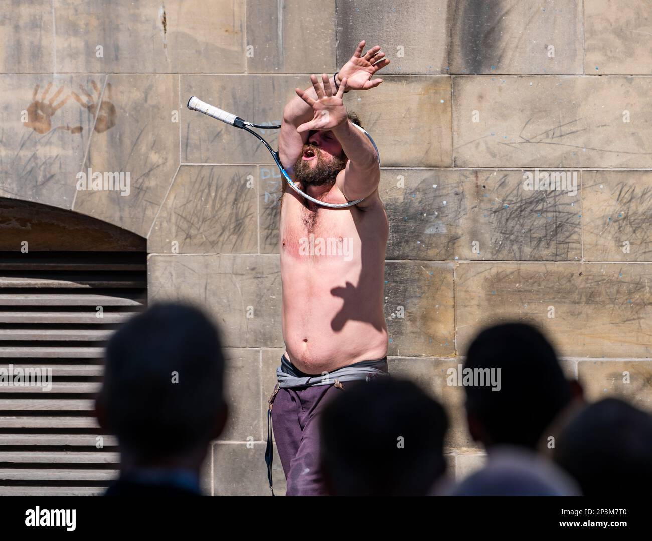Contorsionista di Street entertainer che si esibisce durante il festival con una racchetta da tennis, Royal Mile, Edimburgo, Scozia, Regno Unito Foto Stock