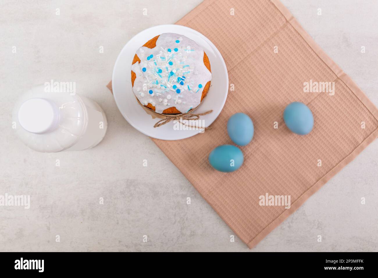 Torta di Pasqua russa, uova colorate su un tovagliolo e bottiglia di latte, su un tavolo leggero. Buon poster di pasqua e banner per il testo di saluto. Vista dall'alto Foto Stock