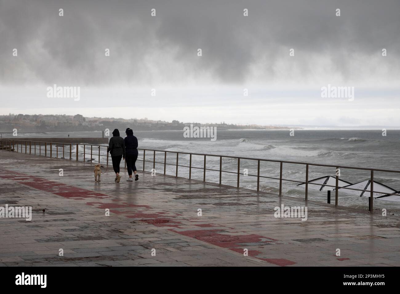 Dog walkers sul lungomare in tempo tempesta, Cascais, Lisbona Regione, Portogallo, Europa Foto Stock