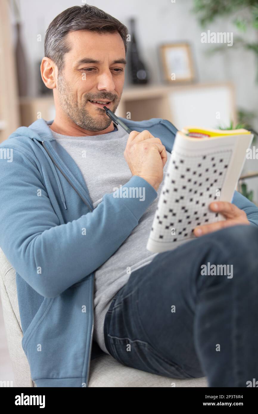 giovane uomo seduto facendo un puzzle crossword Foto Stock