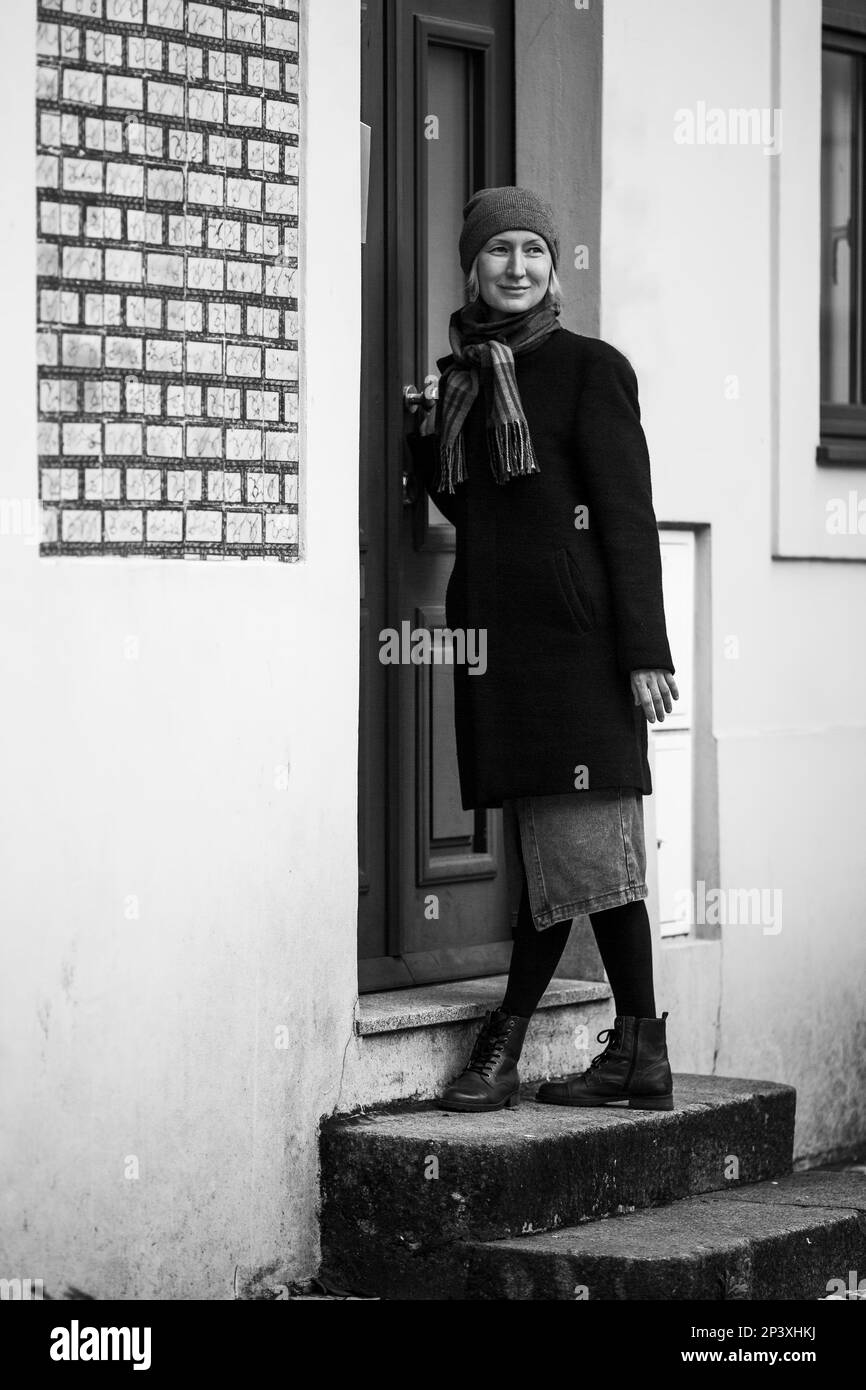 Una donna in piedi accanto alla porta di una casa. Una fotografia in bianco e nero. Foto Stock