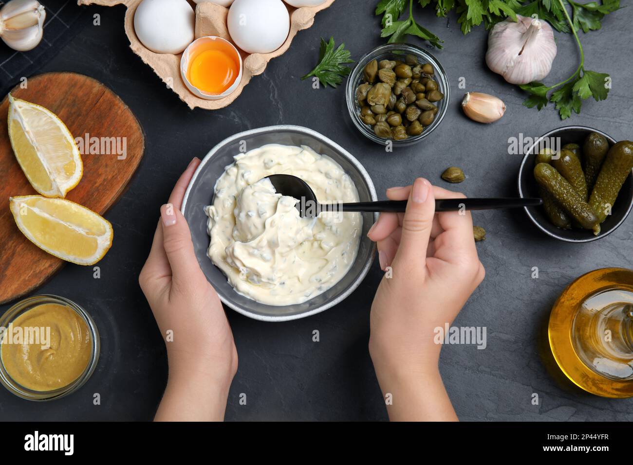Donna con salsa tartara al tavolo nero, vista dall'alto Foto Stock