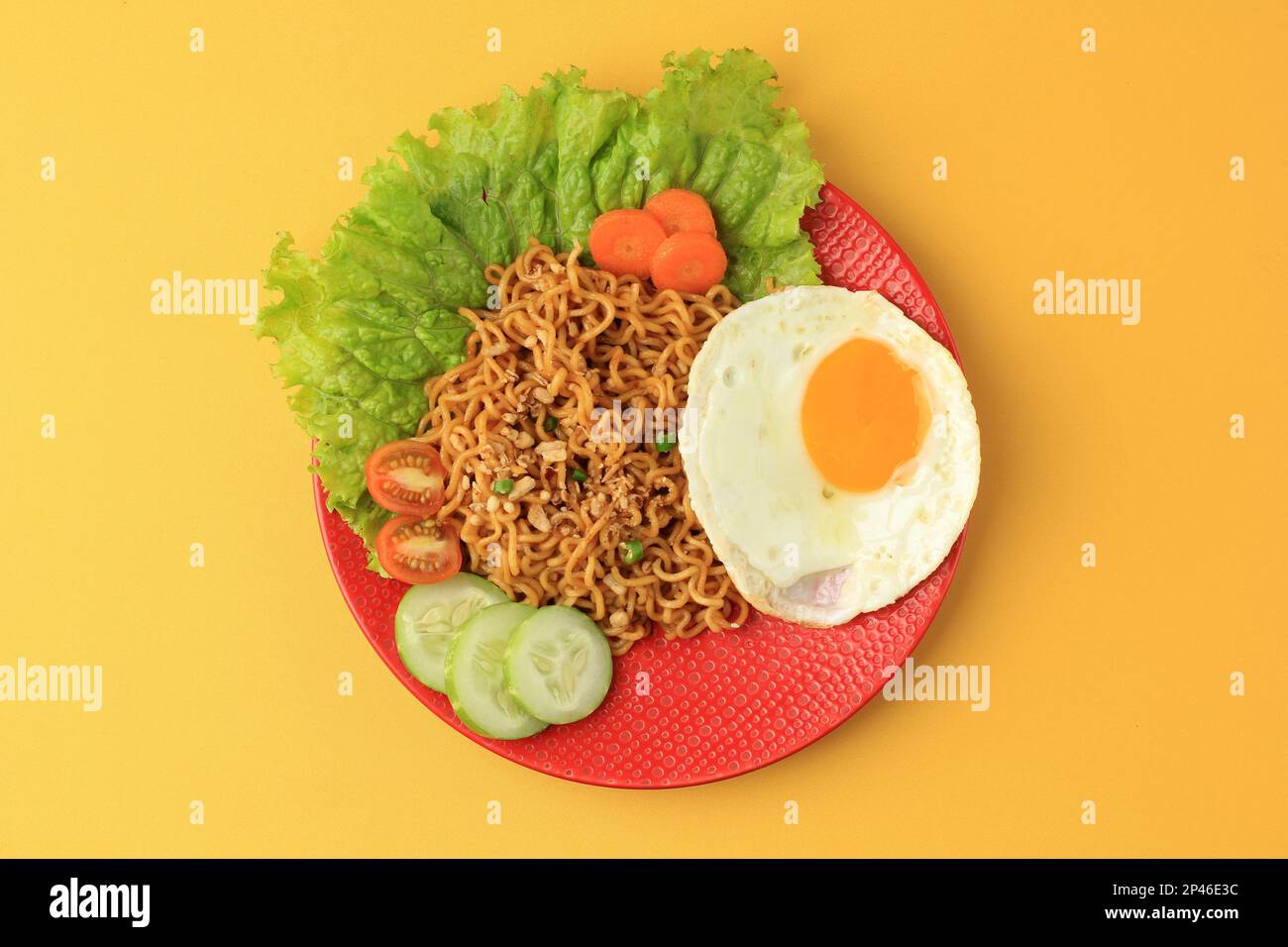 Top View Indomie Goreng. Indonesiano Instant Noodle con uovo lato soleggiato, sul tavolo giallo Foto Stock