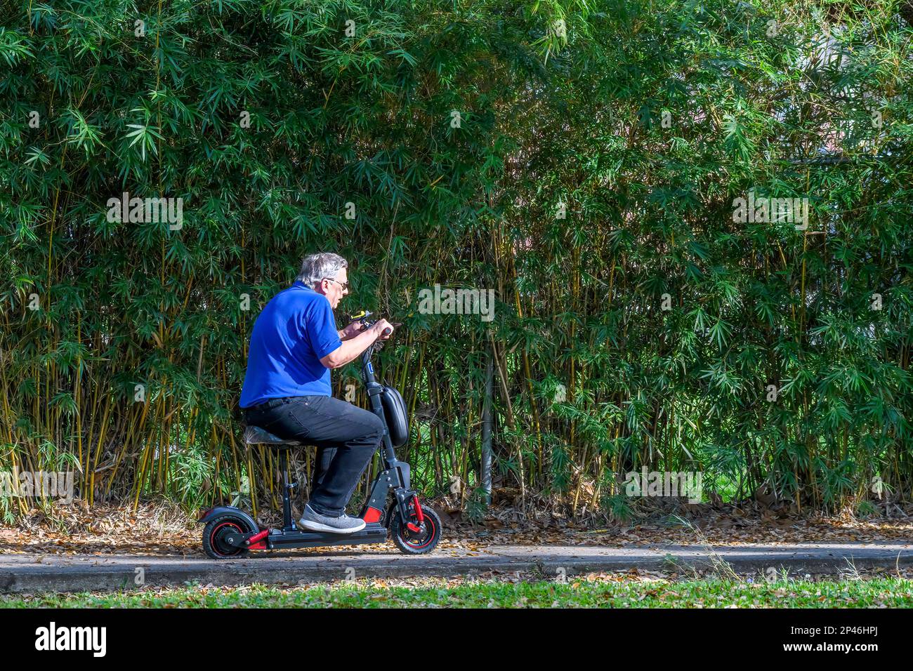 NEW ORLEANS, LA, USA - 1 MARZO 2023: L'uomo anziano corre sul marciapiede sul suo scooter motorizzato vicino al Parco Audubon Foto Stock