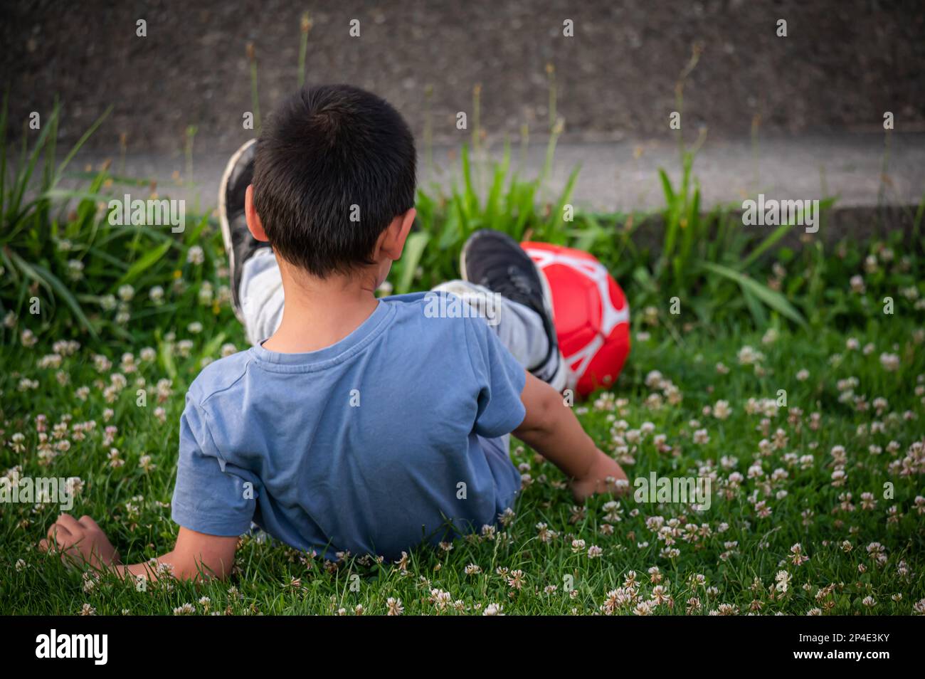 Bambini che giocano a calcio. Un ragazzo asiatico che cade in primavera. Foto Stock