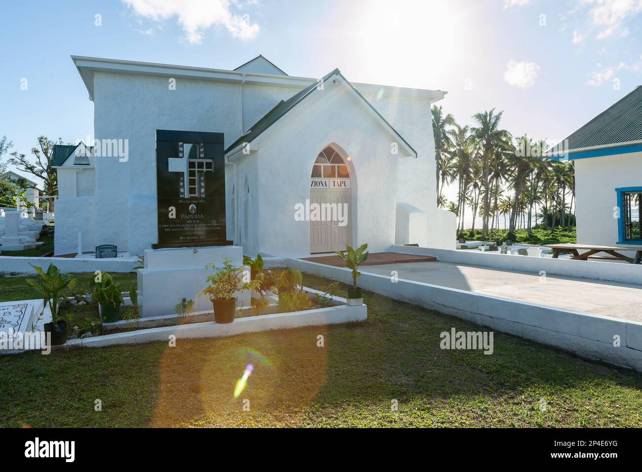 Aitutaki Cook Islands - 8 2010 novembre; percorso che conduce a Ziona tapu segno su porta chiusa chiesa bianca con sole dietro ed effetto lente-flare. Foto Stock