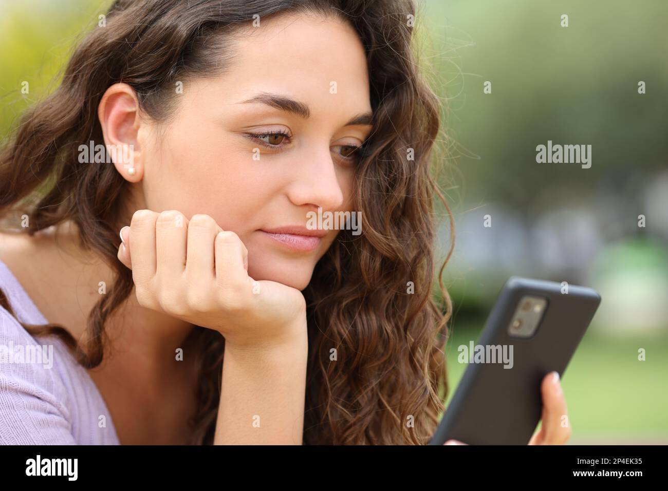 Donna che usa uno smartphone all'aperto in un parco Foto Stock