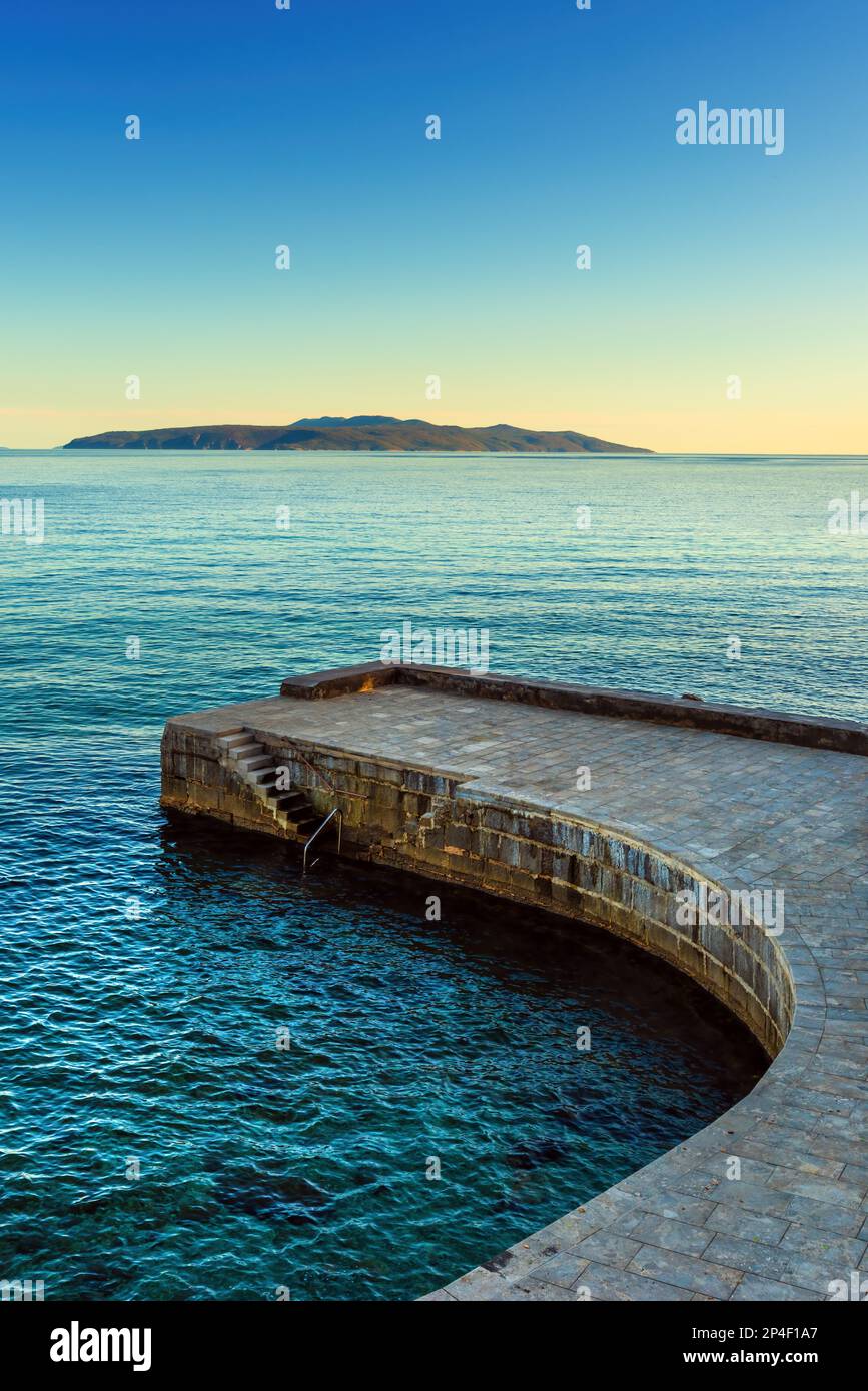 Scale in cemento e molo in pietra nella città di Lovran, nel golfo del Quarnero del mare Adriatico al tramonto Foto Stock