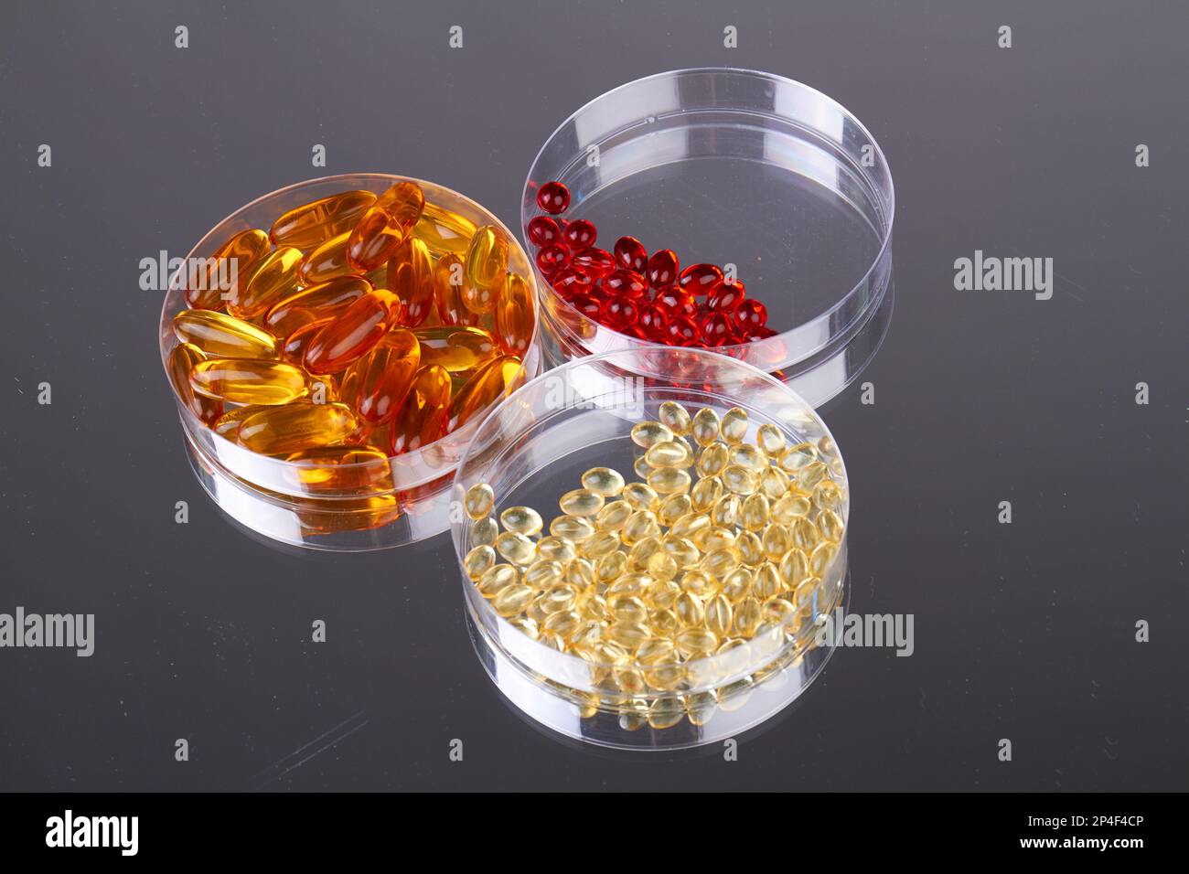 Vista dall'alto tre piatti Petri con pillole vitaminiche. Concetto di ricerca farmaceutica. Foto Stock