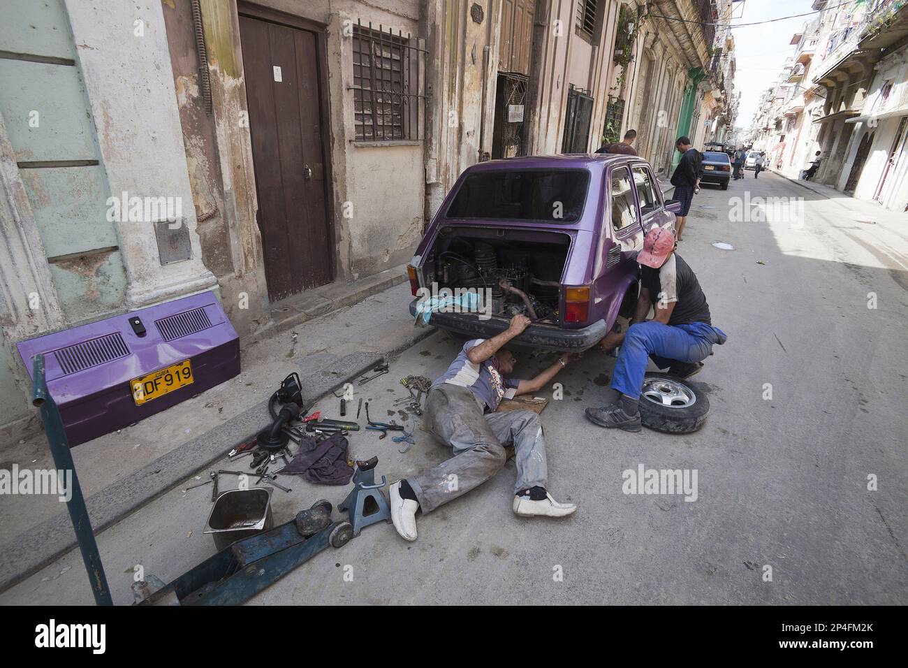 Uomini che riparano vecchia auto polacca a l'Avana Foto Stock